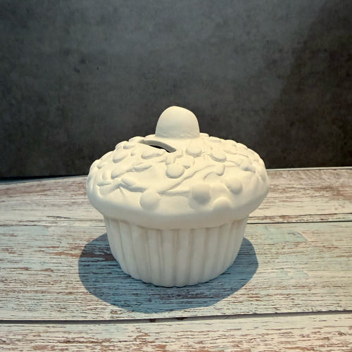White ceramic cupcake-shaped container on a wooden surface with a gray background