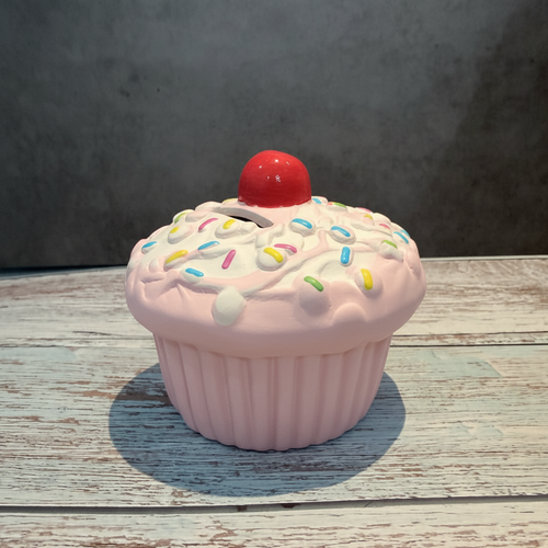 White ceramic cupcake-shaped container on a wooden surface with a gray background