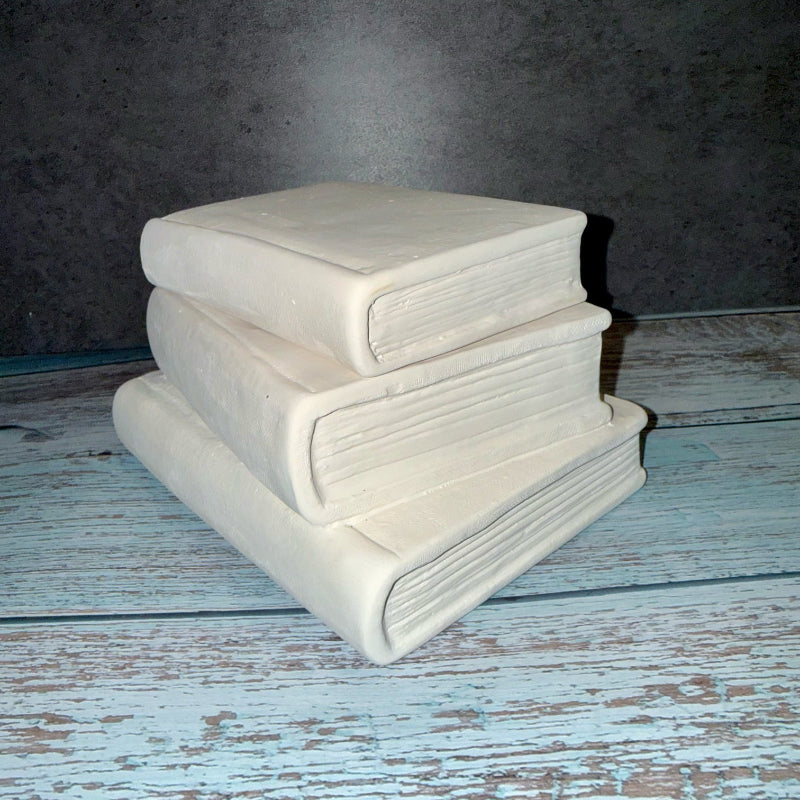 Stack of books on a textured wooden surface with a dark background