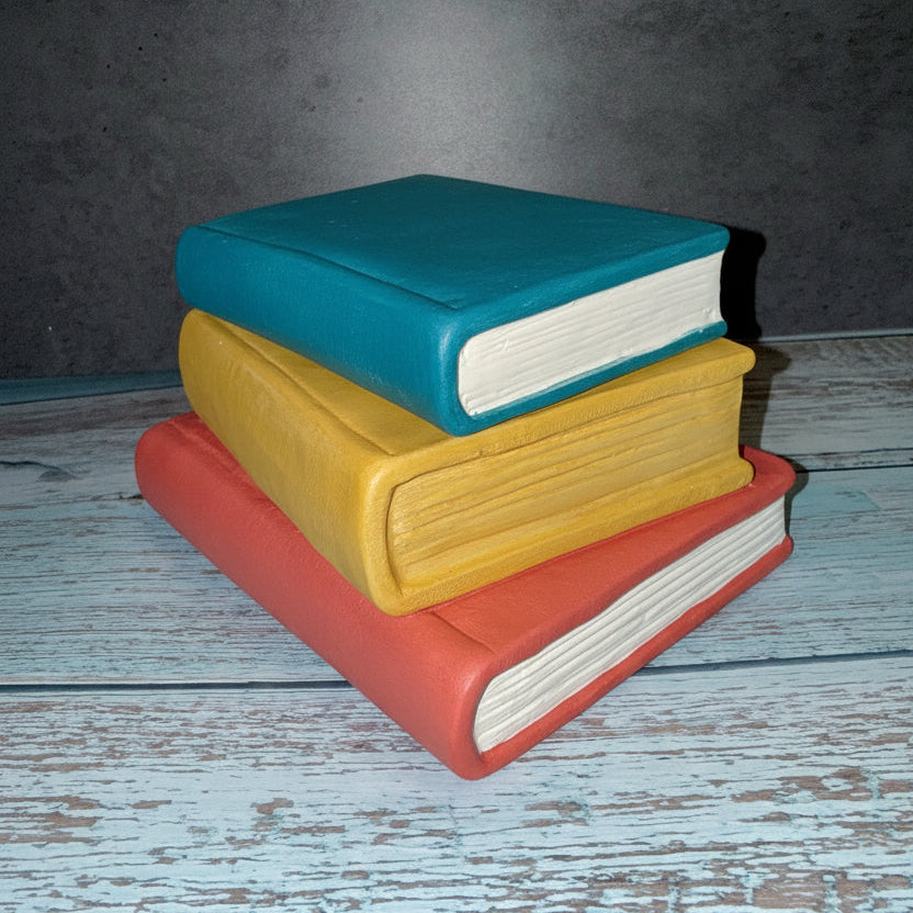 Stack of books on a textured wooden surface with a dark background