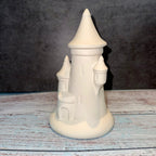 Unpainted ceramic castle on a wooden surface with a dark background