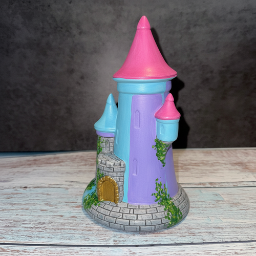 Unpainted ceramic castle on a wooden surface with a dark background