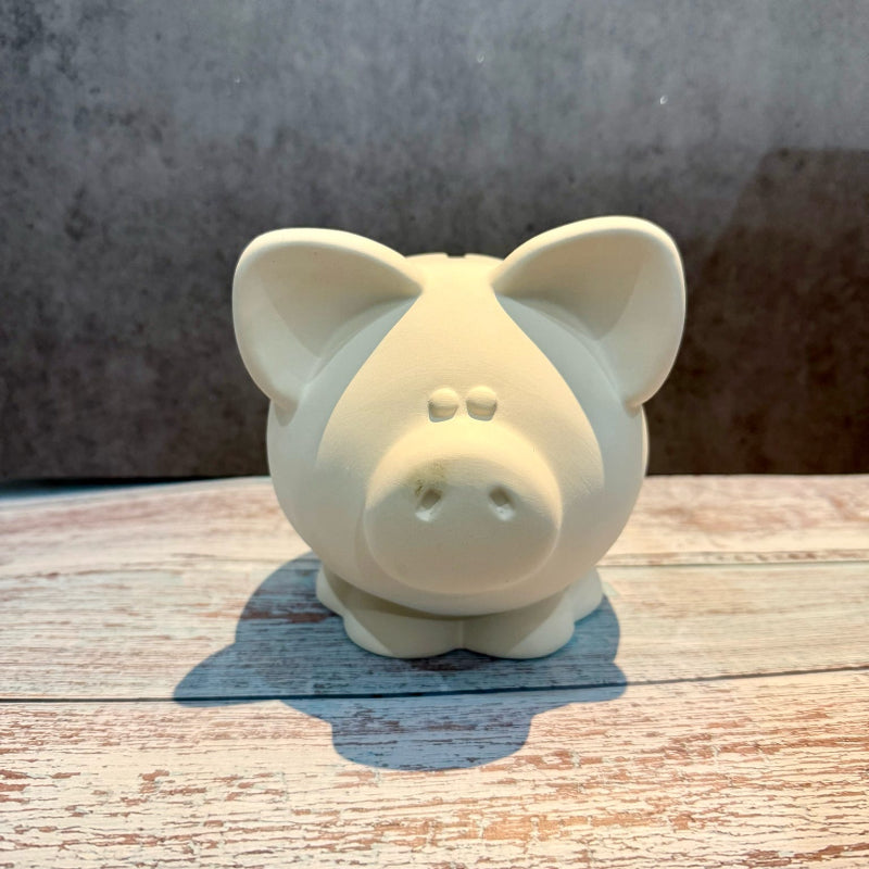 White ceramic piggy bank on a wooden surface with a gray background