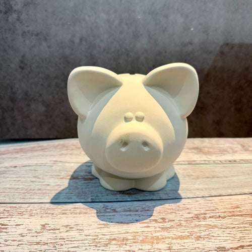 White ceramic piggy bank on a wooden surface with a gray background
