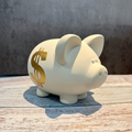 White ceramic piggy bank on a wooden surface with a gray background