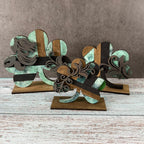 Decorative metal sculpture with floral patterns on a wooden base against a gray background