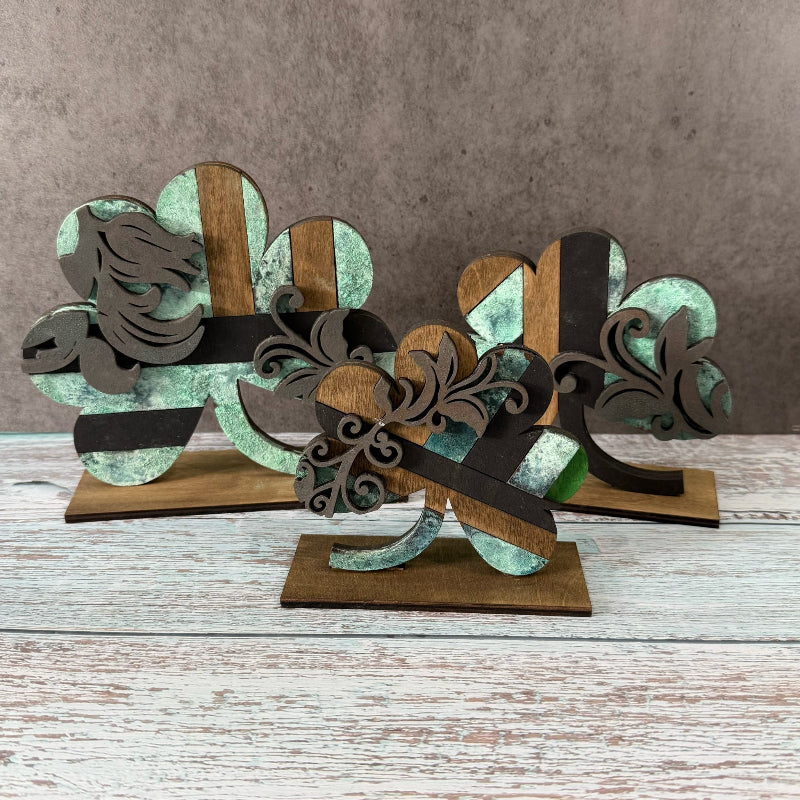 Decorative metal sculpture with floral patterns on a wooden base against a gray background