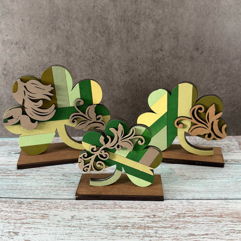 Decorative wooden shamrock cutouts on a wooden surface with a gray background