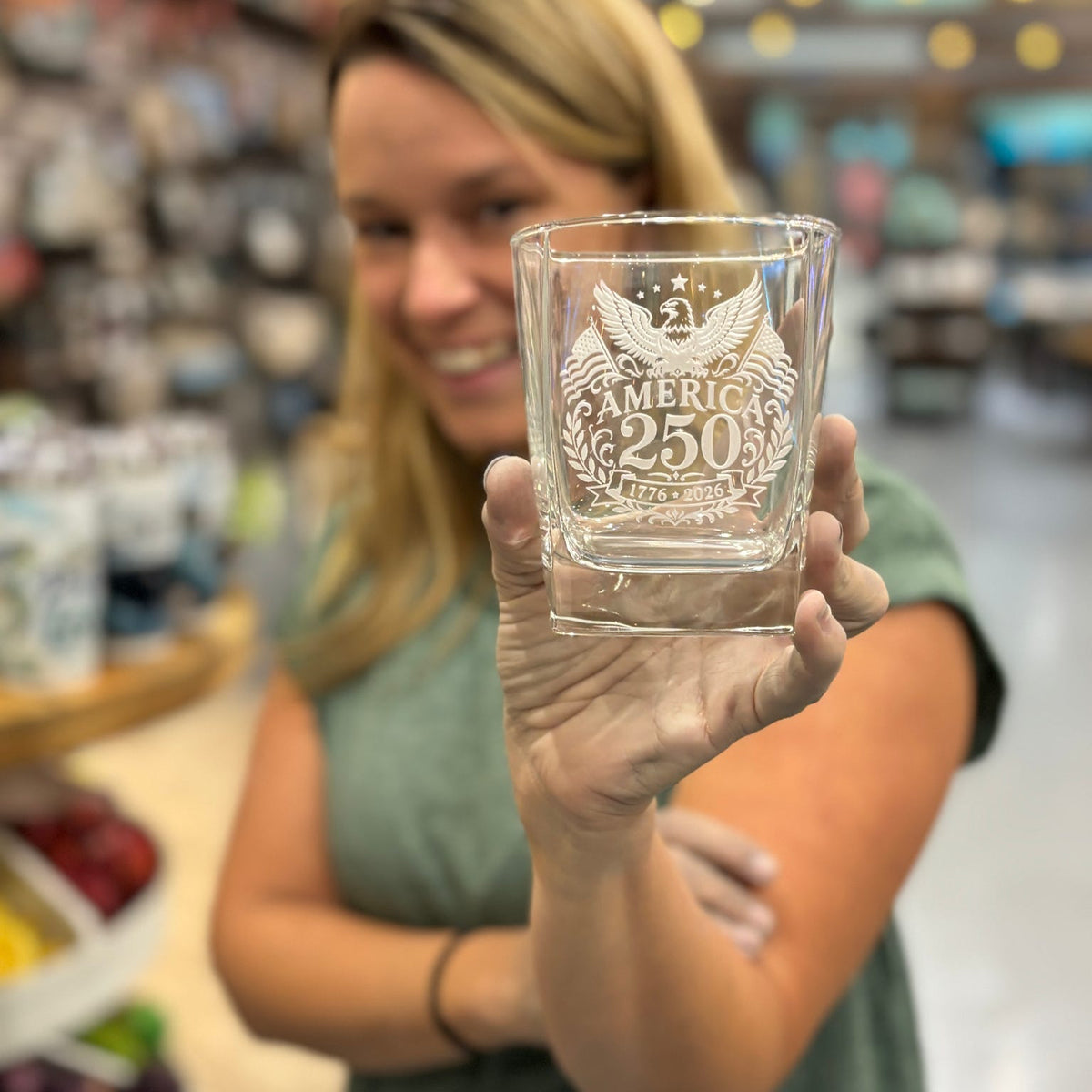 Woman holding a glass with engraved text in a store setting