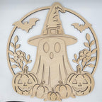 A light natural wood Halloween decorative cutout featuring a ghost in a witch hat, surrounded by bats, flowers, pumpkins, and a circular frame, photographed against a plain light background.