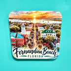 A square coaster with rounded corners featuring a colorful watercolor illustration of Fernandina Beach, Florida, with the text 'Fernandina Beach FLORIDA' at the bottom, shown on a solid turquoise background.