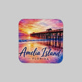 A square magnet with rounded corners featuring a colorful watercolor-style illustration of an Amelia Island, Florida sunset scene with a pier extending over the ocean. The text 'Amelia Island FLORIDA' is printed across the bottom in blue script and serif fonts.