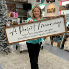 Woman holding a large wooden sign with a quote in a store setting.