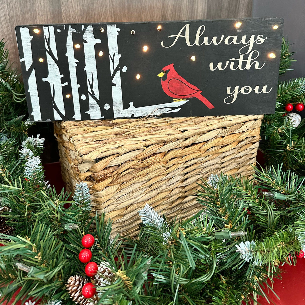 A lighted sign with a cardinal bird design, surrounded by Christmas decorations like lights and ornaments.