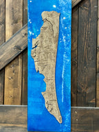 A vertical wooden plaque featuring a laser-cut map of Israel in the center, set against a vibrant blue resin background with white distressed splatters, displayed on a rustic dark wood plank surface.