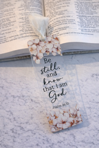 Floral bookmark with 'Be still and know that I am God' text on a marble surface