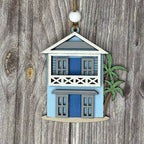 Decorative house ornament with blue doors and white trim on a wooden background