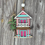 Decorative miniature hut with a green plant on a wooden background