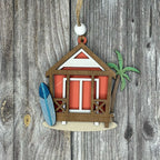 Decorative ornament of a beach hut with a palm tree and surfboard on a wooden background