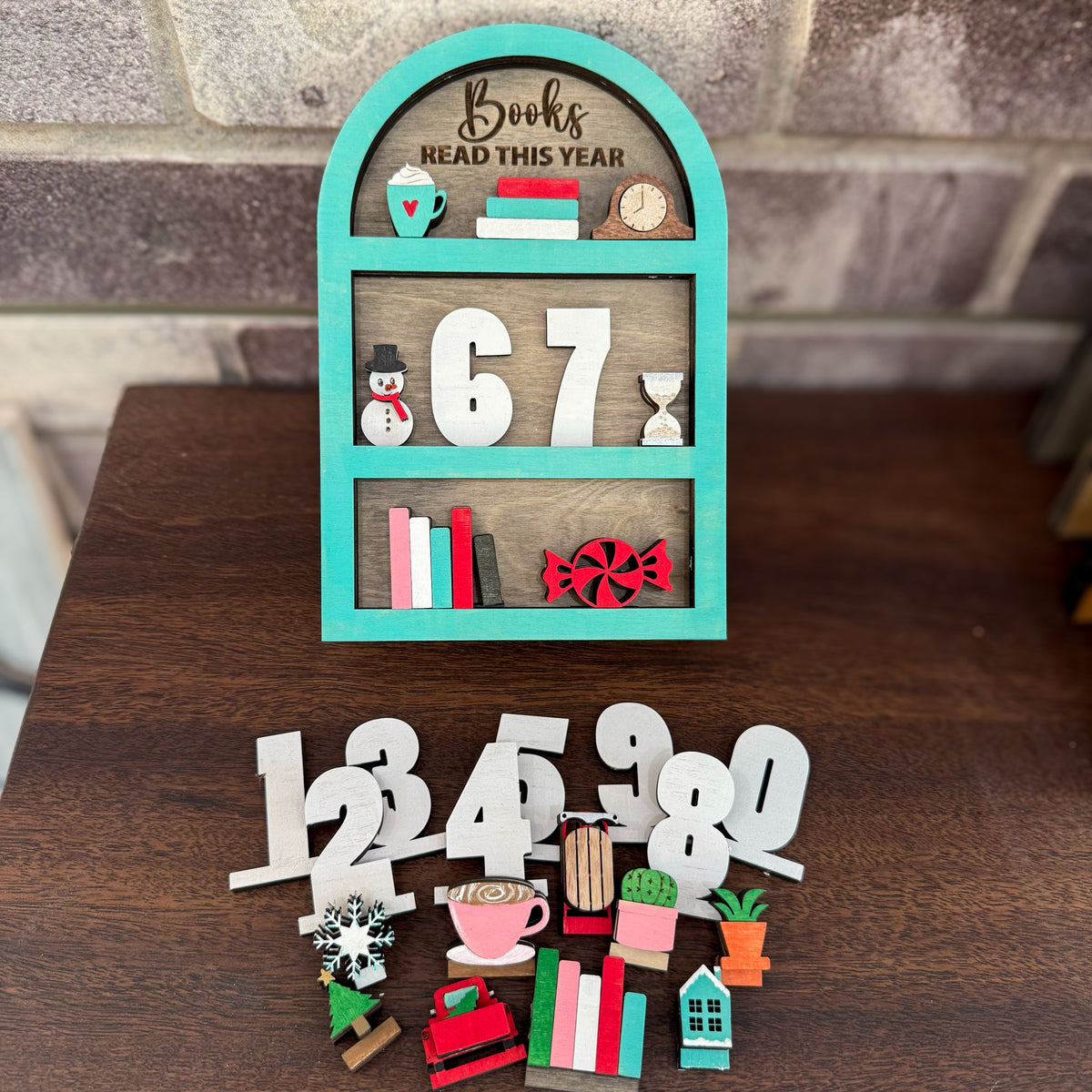 Decorative book tracker shelf with numbers and small items on a wooden surface