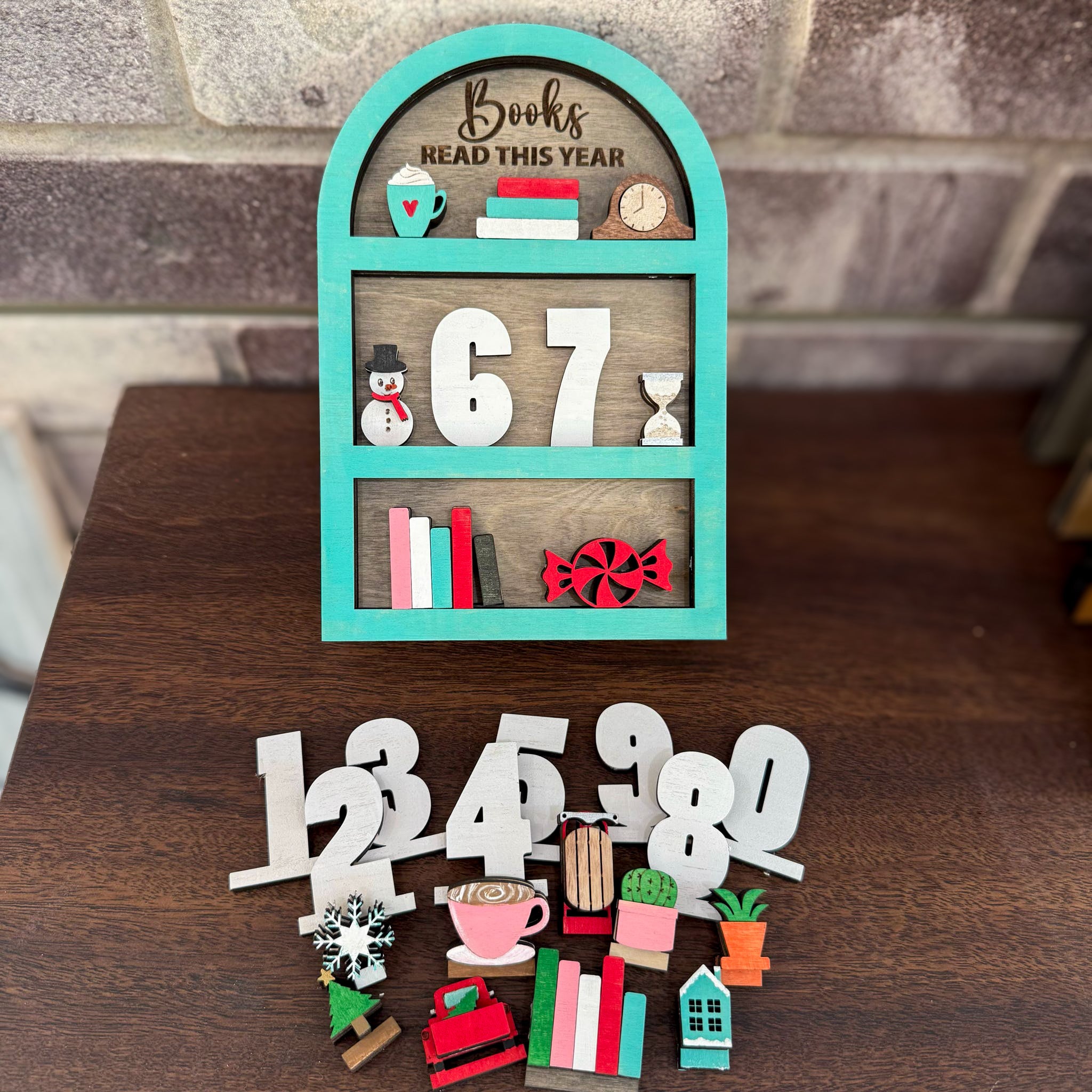 Decorative book tracker shelf with numbers and small items on a wooden surface