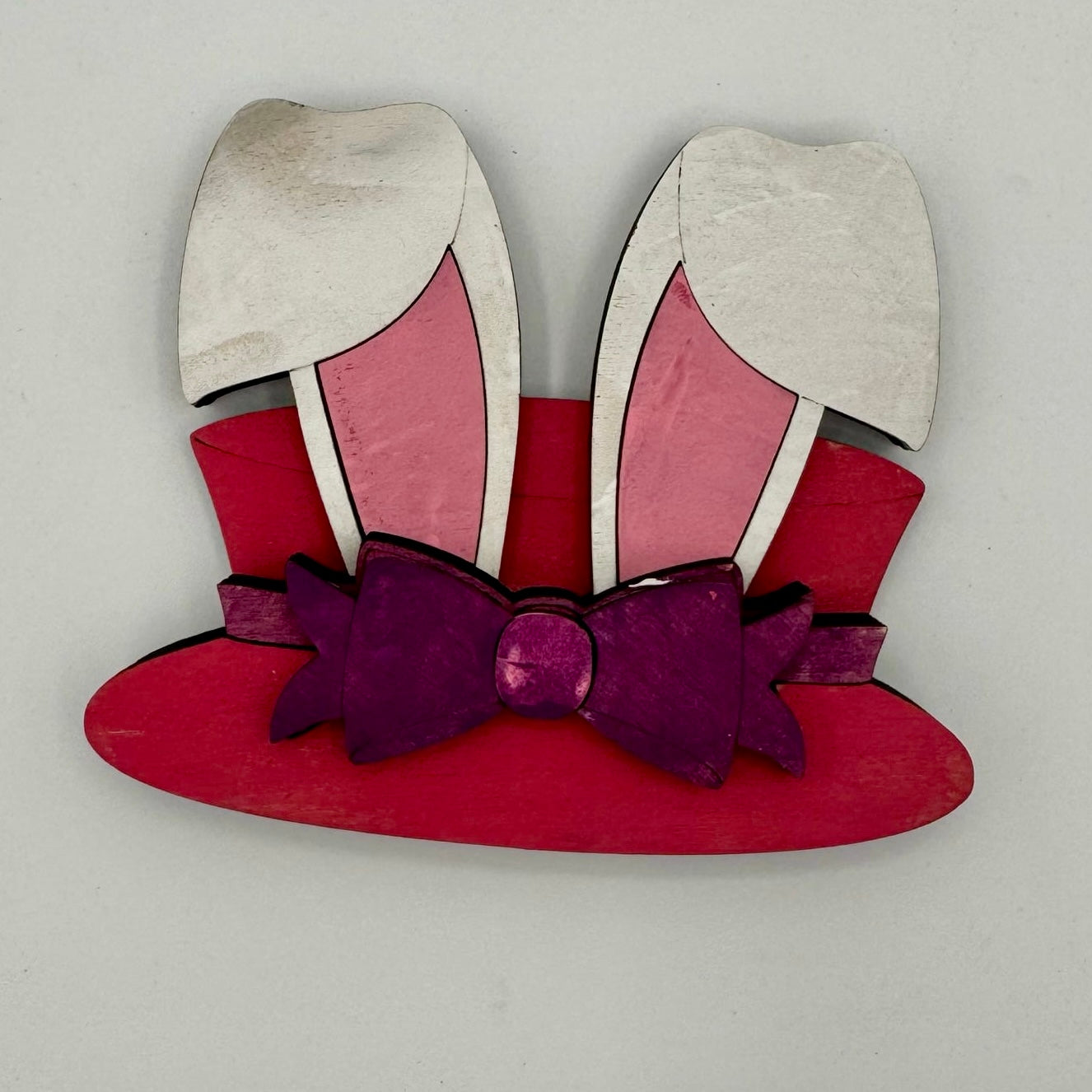 Red bunny ears with a purple bow on a gray background