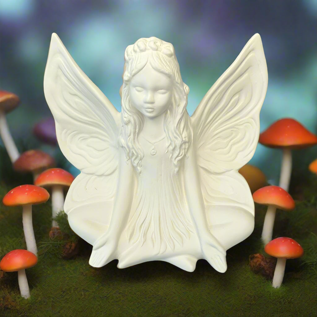 White ceramic fairy figurine with butterfly wings on a wooden surface