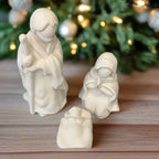 Two white ceramic nativity figures on a wooden surface