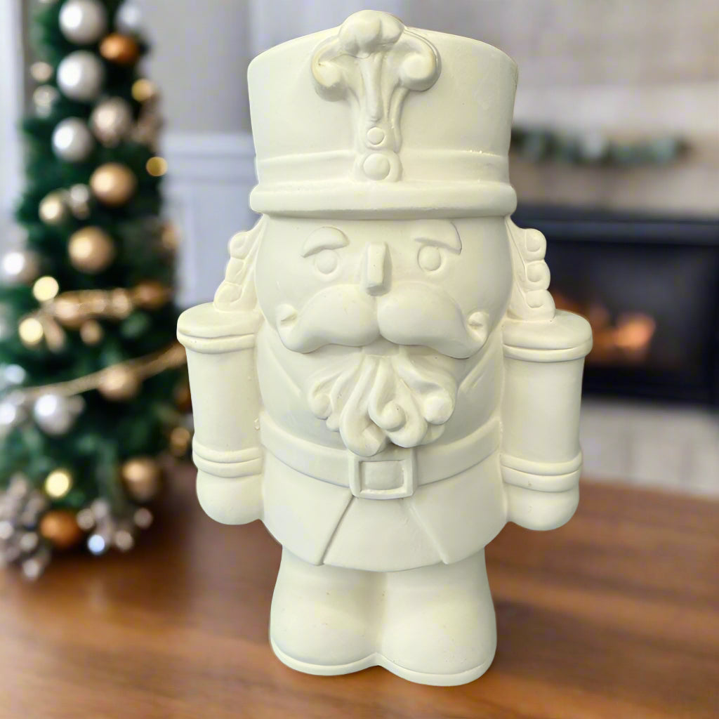 Unpainted ceramic nutcracker figurine on a wooden surface