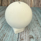 White ceramic ball with embossed design on a wooden surface
