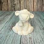 White ceramic lamb figurine on a wooden surface with a rustic background