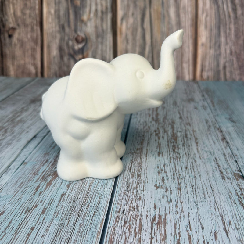White ceramic elephant figurine on a wooden surface with a rustic background