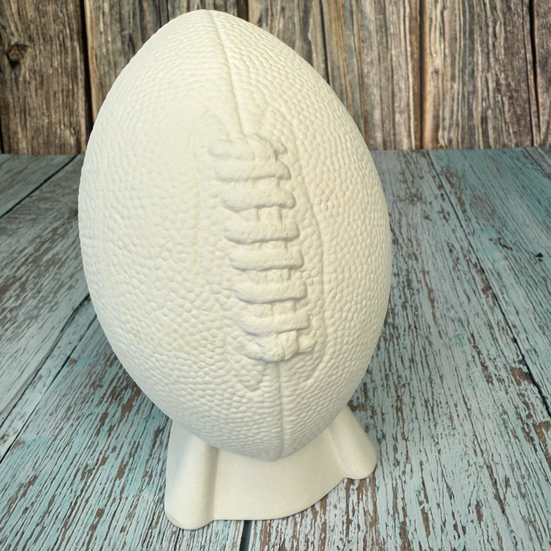 White textured football on a stand against a wooden background