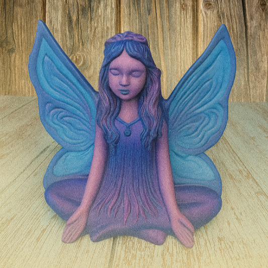 Decorative figurine of a fairy with blue wings on a wooden surface