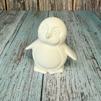 White ceramic penguin on a wooden surface with a rustic background