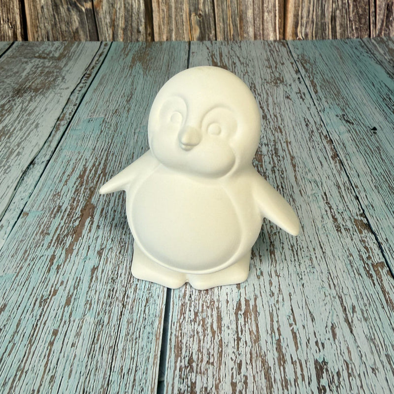 White ceramic penguin on a wooden surface with a rustic background