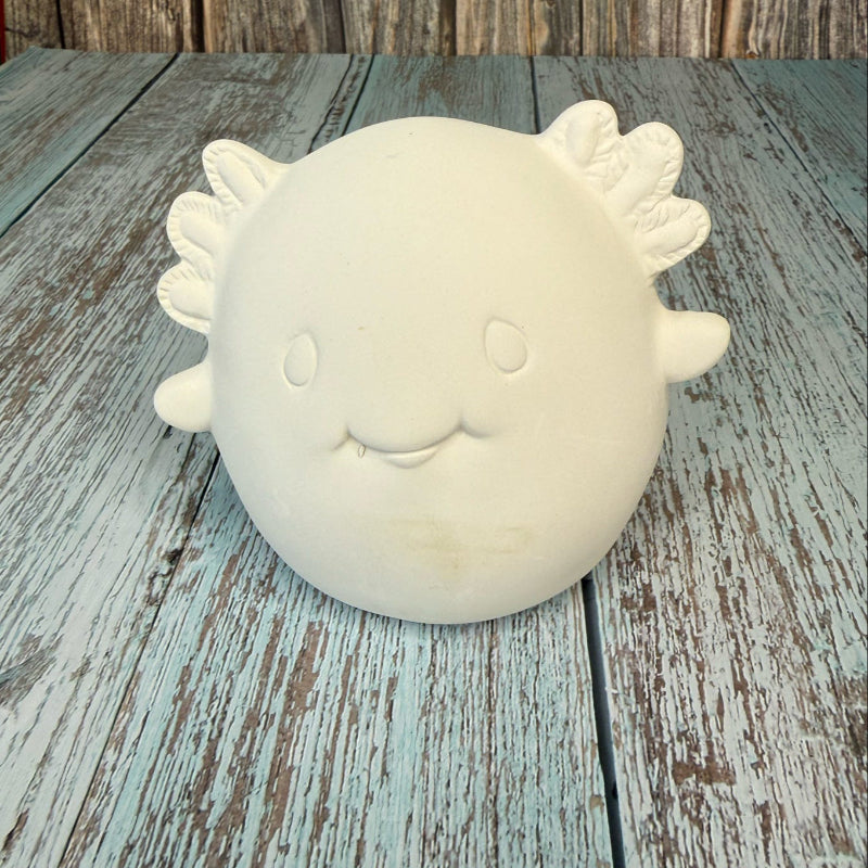 White ceramic sun-shaped object on a wooden surface with a rustic background