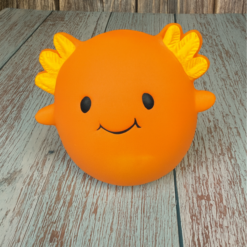 Orange sun-shaped object with a face on a wooden surface