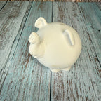 White ceramic piggy bank on a rustic wooden surface