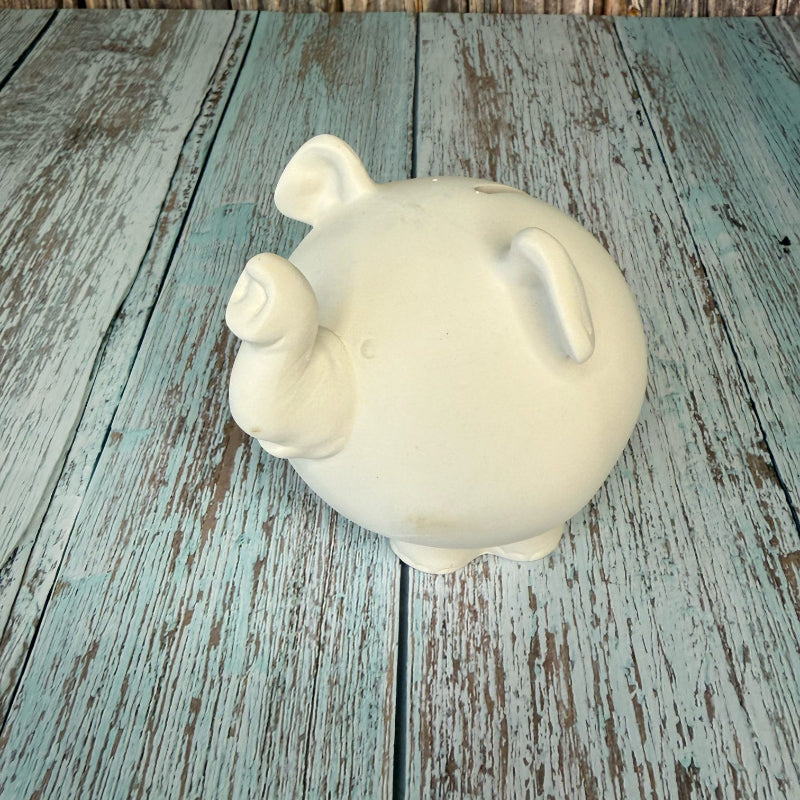 White ceramic piggy bank on a rustic wooden surface