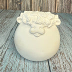 White ceramic pot with decorative top on a wooden surface