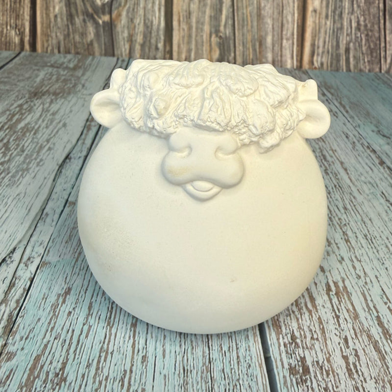White ceramic pot with decorative top on a wooden surface