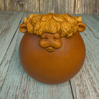 Ceramic pot with a face design on a wooden surface