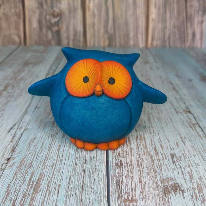 Blue owl figurine with orange details on a wooden surface