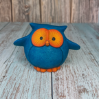 Blue owl figurine with orange details on a wooden surface