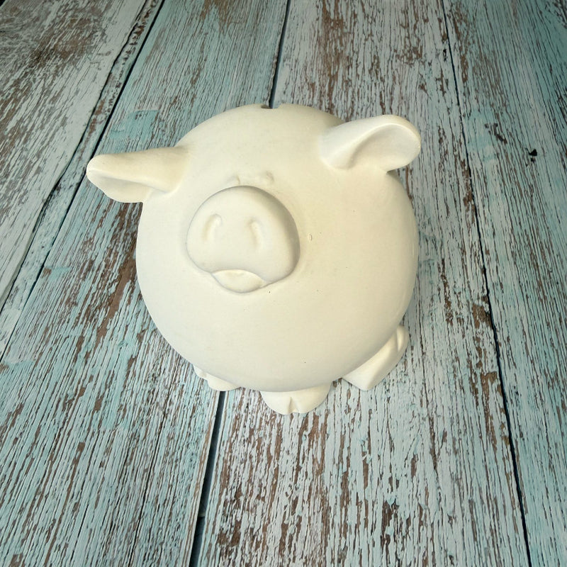 White ceramic pig on a rustic wooden surface