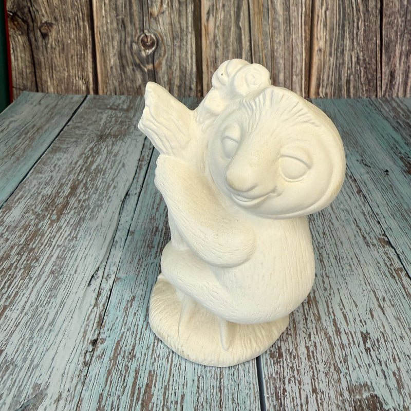 Unpainted ceramic sculpture of a bird on a wooden surface