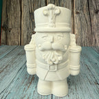 Unpainted ceramic nutcracker figurine on a wooden surface