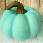 Turquoise pumpkin with a brown stem on a wooden surface
