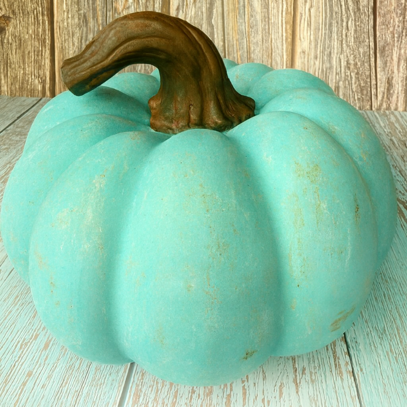 Turquoise pumpkin with a brown stem on a wooden surface